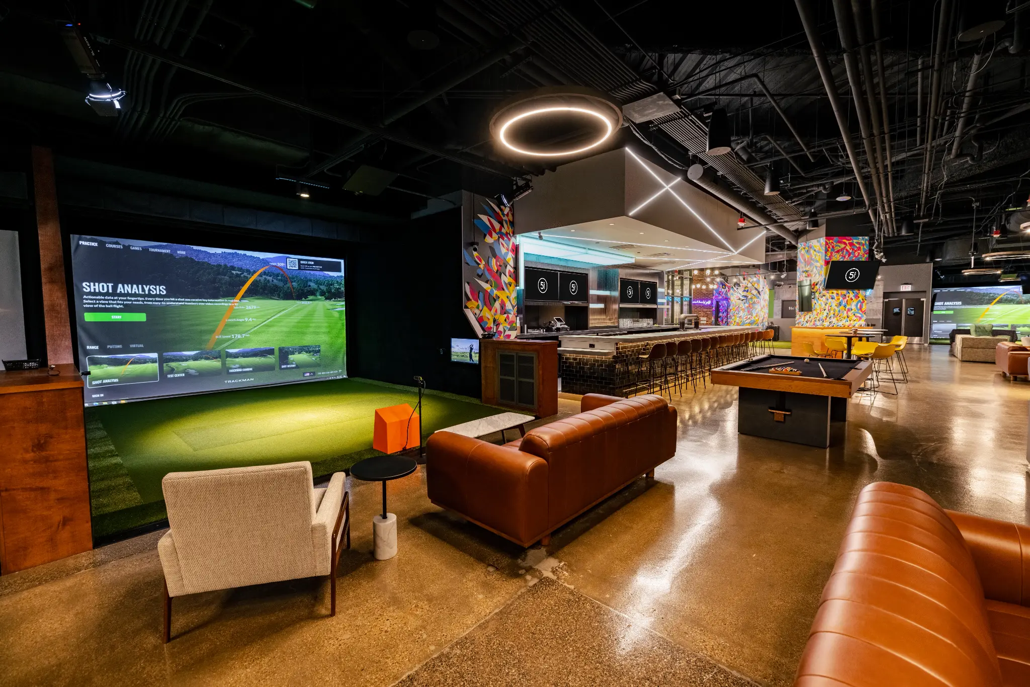 Open simulator bays, bar seating, and social space in a Five Iron Core environment